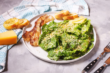Caesar salad with crispy bread and bacon close up on concrete background