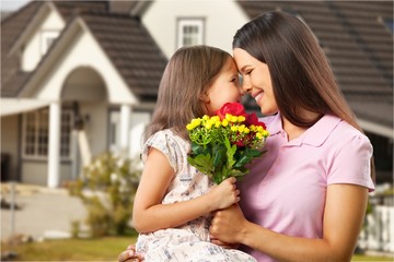 Fototapeta na wymiar Mother and daughter with a bouquet of flowers on house background.