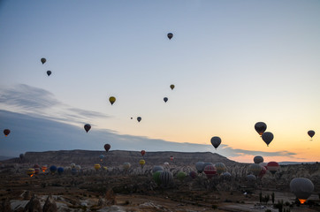 The sunrise in the mountains with Hot air balloons flying over Cappadocia red valley in the sky. Travel to Goreme, Turkey
