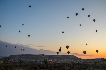 The sunrise in the mountains with Hot air balloons flying over Cappadocia red valley in the sky. Travel to Goreme, Turkey