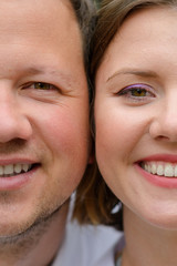 Face of man and woman close-up. The couple is looking into the frame. Gender of a woman’s face and gender of a man’s face. Comparison of man and woman. Both are smiling.