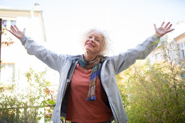 elderly woman happy with arms outstretched outside