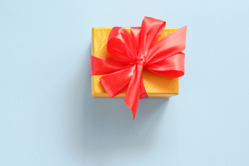 Gift box with red bow on a blue background. Flat lay