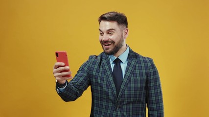 Smiling young business employee in suit laughing at fun content on smartphone reading news message posing on background. Modern people lifestyle. Copy space.
