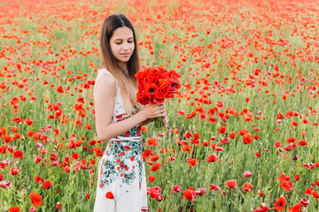 beautiful girl in a poppy field at sunset. concept of freedom