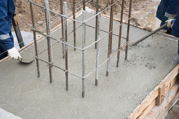 The process of compacting and smoothing fresh concrete. Concrete is poured into the formwork with rebar. Workers level the concrete surface.