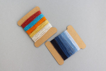 palette of blue and multicolored spool of threads for jeans custom work on light grey background