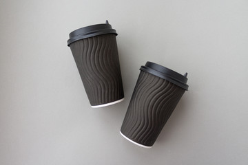 Coffee to go concept. Disposable black cup with spiral texture with black plastic cover on a trendy grey background. Place for text. Flat lay style. Top view