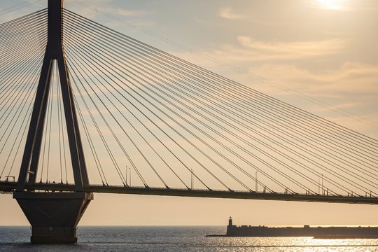 The famous cable bridge Charilaos Trikoupis in Rio Antirio Greece against a warm orange sky during sunset