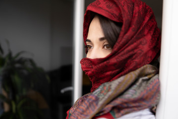 Woman with red scarf looking at the landscape through the balcony window