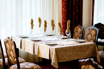 Glasses knife served for dinner in restaurant with cozy interior, wine on a table decorated for an event celebration