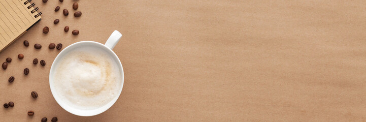 Coffee in a white cup on a brown background. Copy space. Panorama