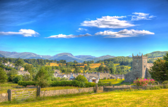 Traditional English country village in Lake District Hawkshead Cumbria in summer with blue sky church and red roses in colourful HDR