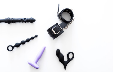 Set of isolated anal sex toys and leather handcuffs at the white background