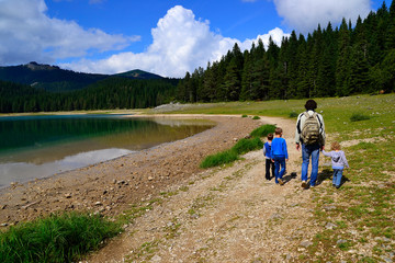 Father with children walk along the shore of Black Lake, Durmitor, Montenegro.