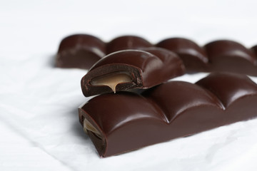Pieces of chocolate with caramel filling on white table, closeup