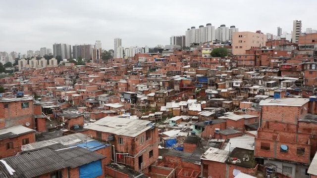 Beautiful aerial view of favela Paraisopolis shanty town with poor brick houses and rich modern buildings in the background in S&atilde;o Paulo, Brazil. Concept of poverty, economic inequality, social class.