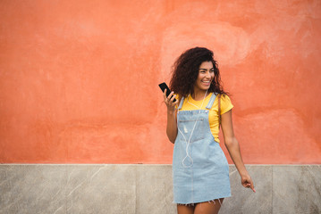 Fototapeta premium beautiful mixed girl listening to the music happy in the street