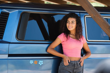 Young woman leaning against a vintage van parked in the camping © Marco Ceron