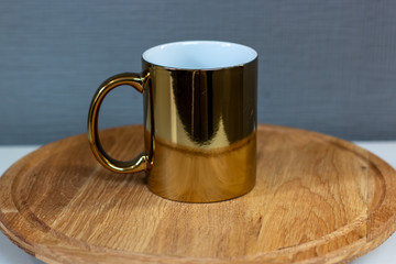 Obraz na płótnie Canvas gold sublimation cup on a wooden stand, chrome mug
