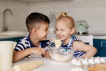 Obraz na płótnie Canvas happy family of funny children, brother and sister, prepare dough, bake cookies in the kitchen