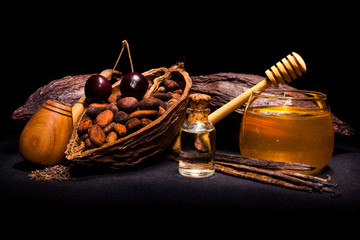 Bottle of oil with cocoa pod and cocoa beans, cherry, bourbon vanilla pods, tobacco pipe and glass...