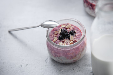 Jar of overnight oats with fresh blueberries and greek yogurt, copyspace with concrete grey background. Close up