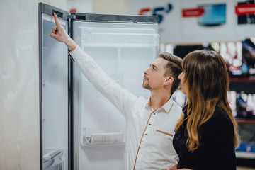 Satisfied customers choosing fridges in appliances store 