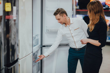 Satisfied customers choosing fridges in appliances store 