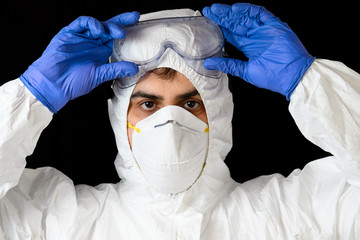 Covid-19 protective equipment. Portrait of Doctor or male nurse Wearing Personal Protective Equiment on black isolated background .