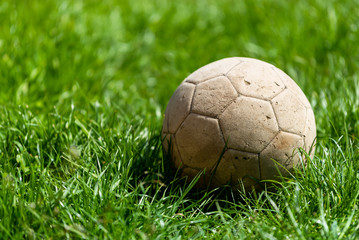 Old soccer ball on a background of green grass