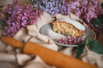 Homemade Apple pie on a wooden table next to a bowl of lilacs. Gentle toning.