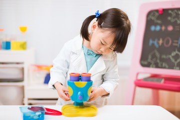 toddler girl pretend play scientist role  at home against white background