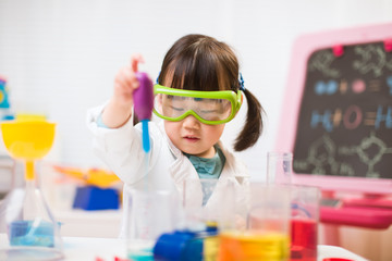 toddler girl pretend play scientist role  at home against white background