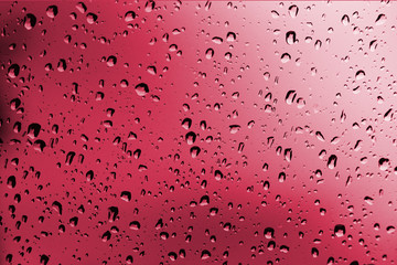 Rainy red background, rain water drops on the window or in shower stall, season backdrop, abstract...