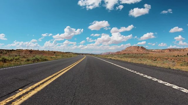 POV Hyperlapse Fast Driving car on asphalt Arizona road with mountains near Grand Canyon. Clear sky with puffy white clouds