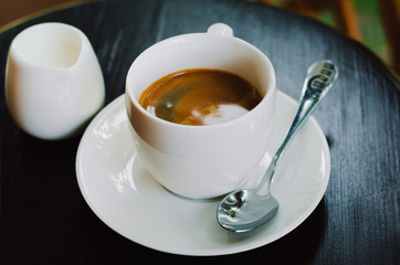 Hot coffee in a white ceramic cup on a wooden table. Morning homemade coffee. Relaxing time concept. Copy space. Selective focus.