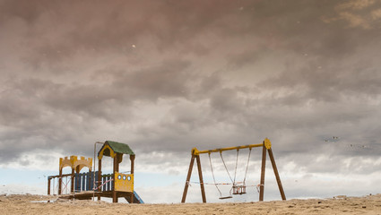Reflection of children's attractions on the beach after the rain.