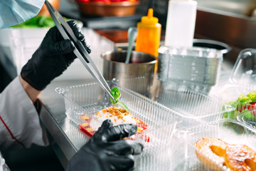 Food delivery in the restaurant. The chef prepares food in the restaurant and packs it in disposable dishes.