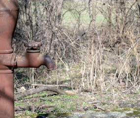 The old well pump still stands in a field in rural southwest Missouri and could still be utilized if necessary. This is a close up view of the old faucet. Bokeh effect.