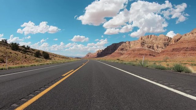 POV Hyperlapse Driving a car on asphalt Arizona desert road with mountains near Grand Canyon. Clear sky with puffy white clouds