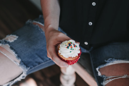 Persona sosteniendo cupcake con vet&uacute;n blanco 