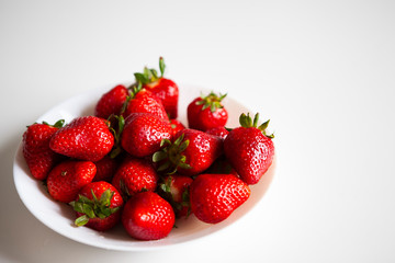 Close up. Fresh ripe delicious strawberries in a white bowl isolated on white background. Beautiful Italian red strawberry. European eco food without pesticides and additives in Milan, Lombardy, Italy