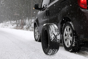 Naklejka premium Snow tire near car on road in winter