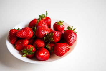 Close up. Fresh ripe delicious strawberries in a white bowl isolated on white background. Beautiful Italian red strawberry. European eco food without pesticides and additives in Milan, Lombardy, Italy