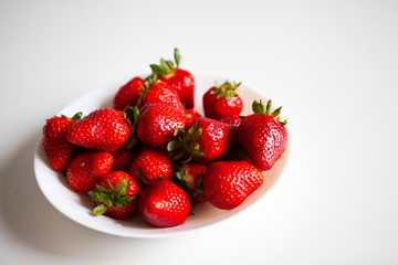 Close up. Fresh ripe delicious strawberries in a white bowl isolated on white background. Beautiful Italian red strawberry. European eco food without pesticides and additives in Milan, Lombardy, Italy