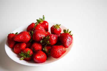 Close up. Fresh ripe delicious strawberries in a white bowl isolated on white background. Beautiful Italian red strawberry. European eco food without pesticides and additives in Milan, Lombardy, Italy