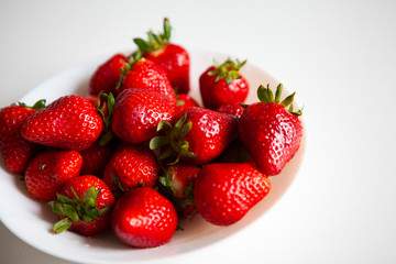 Close up. Fresh ripe delicious strawberries in a white bowl isolated on white background. Beautiful Italian red strawberry. European eco food without pesticides and additives in Milan, Lombardy, Italy