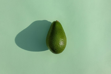 avocado on a colored background top view with a hard shadow