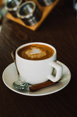 Hot coffee in a white ceramic cup on a wooden table. Morning homemade coffee. Relaxing time concept. Copy space. Selective focus.